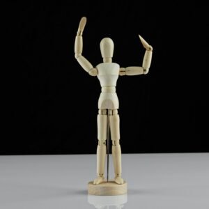 Wooden artist mannequin standing with arms raised on a black background, ideal for art and craft projects.